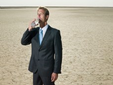 喝着清水在沙漠中凝视前方外国商业男人图片