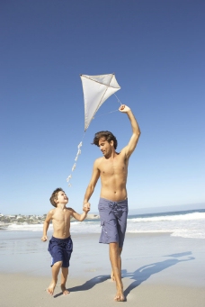 海天一色沙滩上放风筝的父子图片
