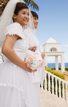 男女礼服穿着婚纱礼服手捧鲜花站在海边远望的男女图片图片