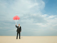 在沙漠中拿着气球的商务男人图片